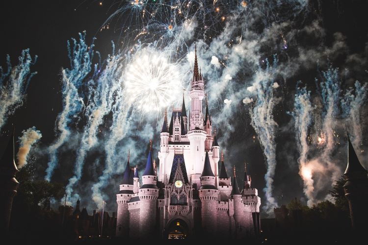 Disney castle with fireworks above it at night