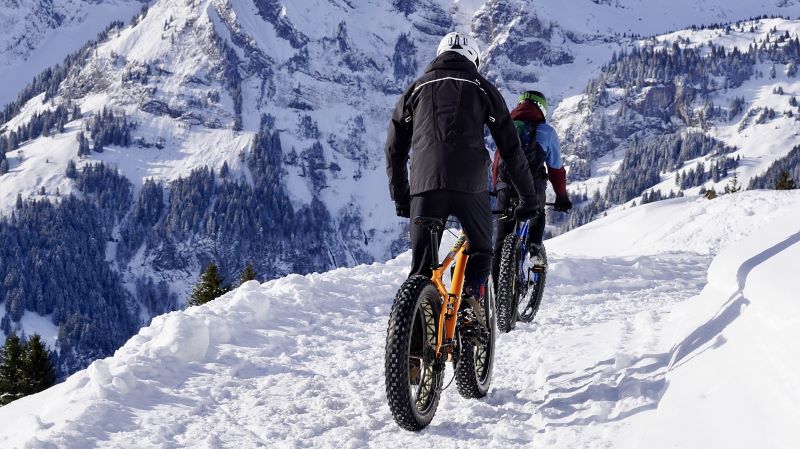 Couple riding bicycles over snowy trails